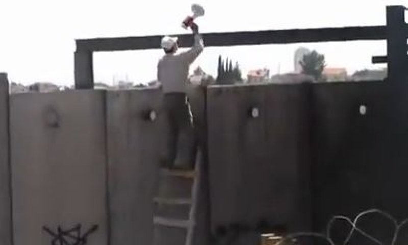 צפו: המפגין הפלסטיני טיפס על גדר ההפרדה וחטף
